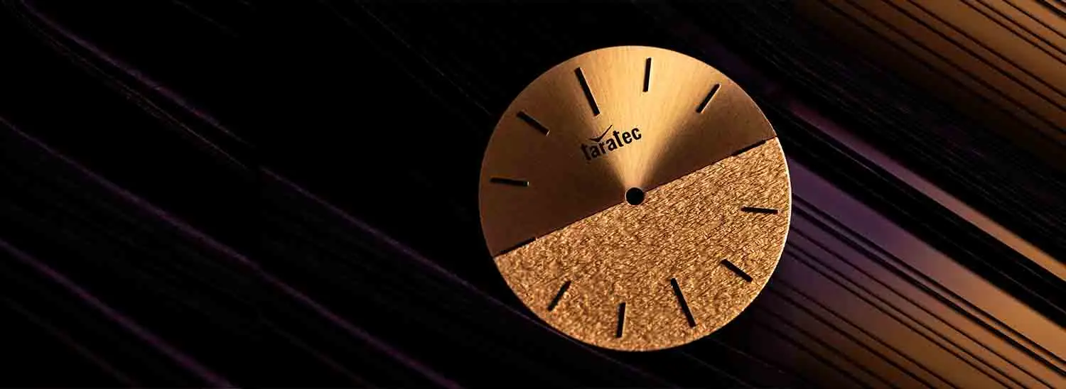 Elegant gold watch dial with a brushed upper half and textured lower half, featuring simple black hour markers